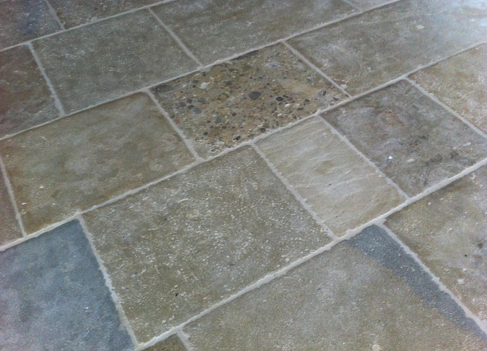 Großformatiger Cotto-Natursteinboden mit warmen Erdtönen und eingelegtem Stein-Dekor