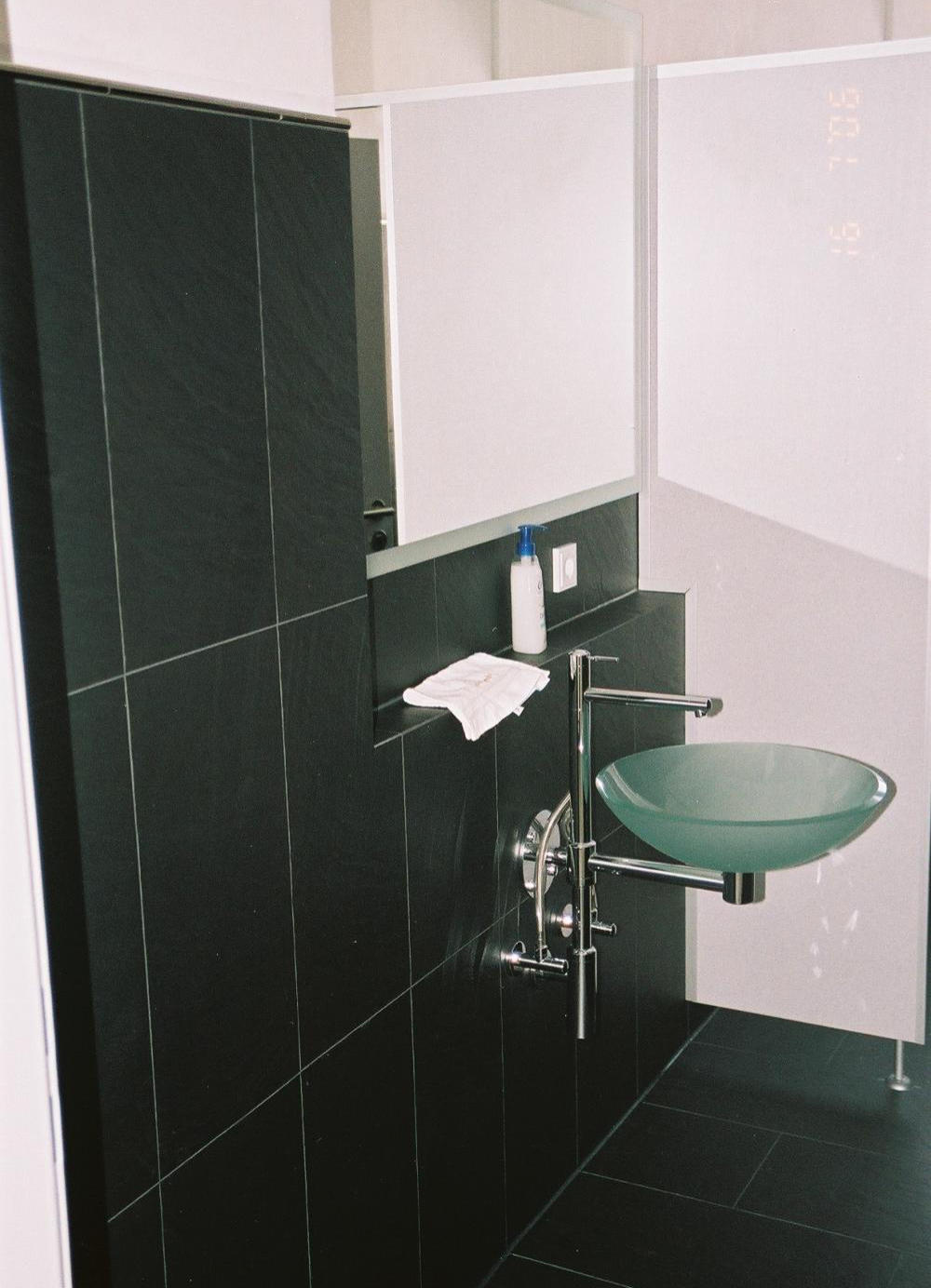 Minimalistisches Bad mit großformatigen dunklen Schiefer-Fliesen und Glas-Waschschale