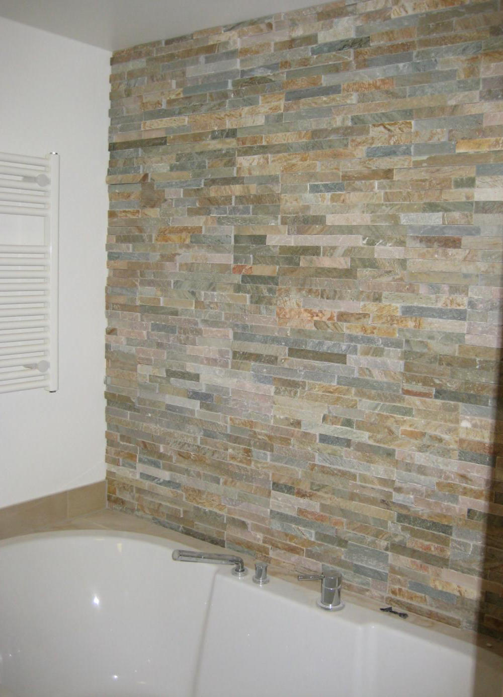 Wandverkleidung aus geschichteten Natursteinriemchen in erdigen Tönen