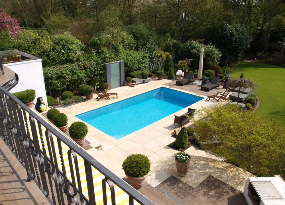 Luxuriöser Außenpool mit Holz-Terrasse, Natursteinumrandung und mediterraner Bepflanzung
